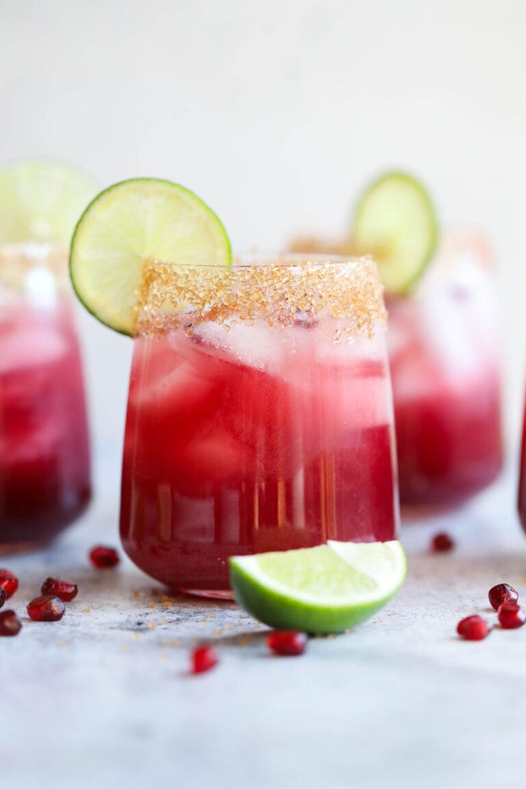 A pomegranate margarita with a lime wheel and sugared rim.
