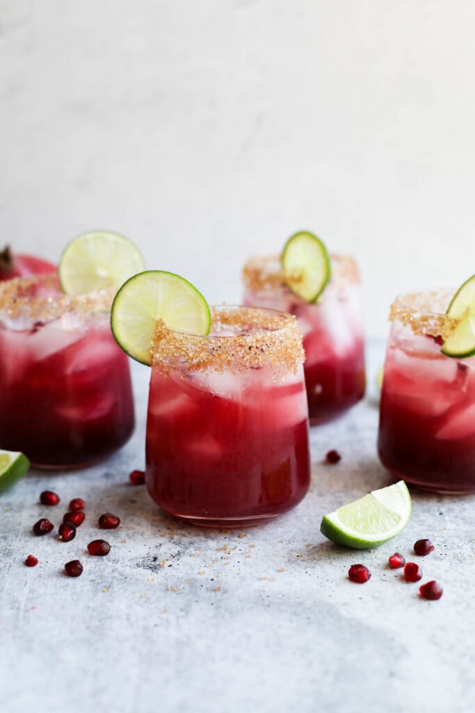 Pomegranate margaritas in a row on a counter top.