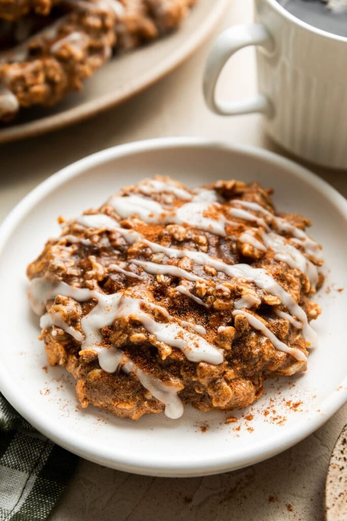A chai spice protein breakfast cookie on a white plate with icing and warm spices on top. 