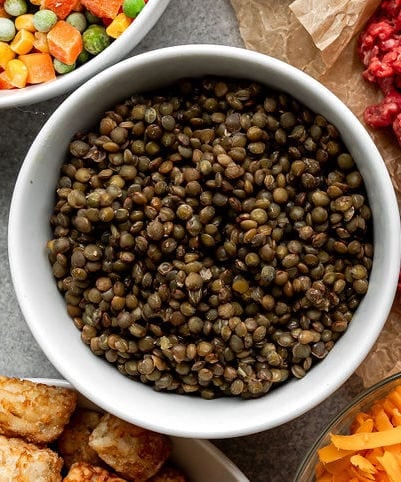 Overhead view of white bowl filled with cooked lentils.