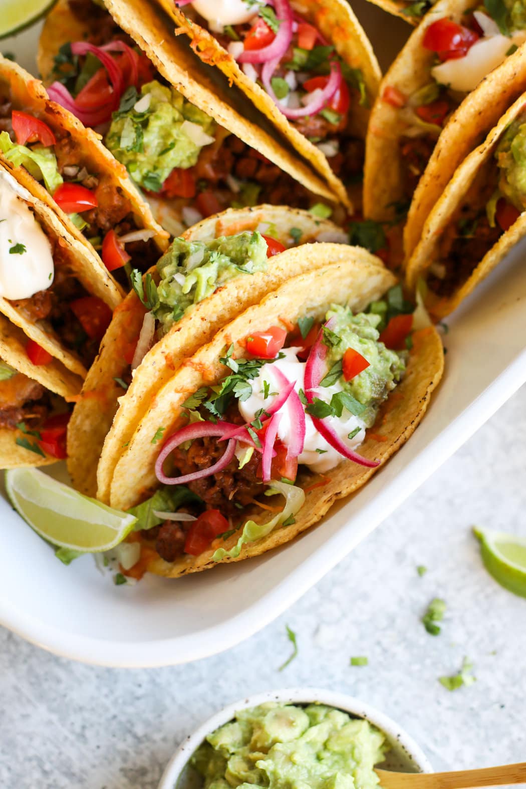 Close up view of fully baked and prepared easy baked tacos topped with fresh toppings and sour cream. 