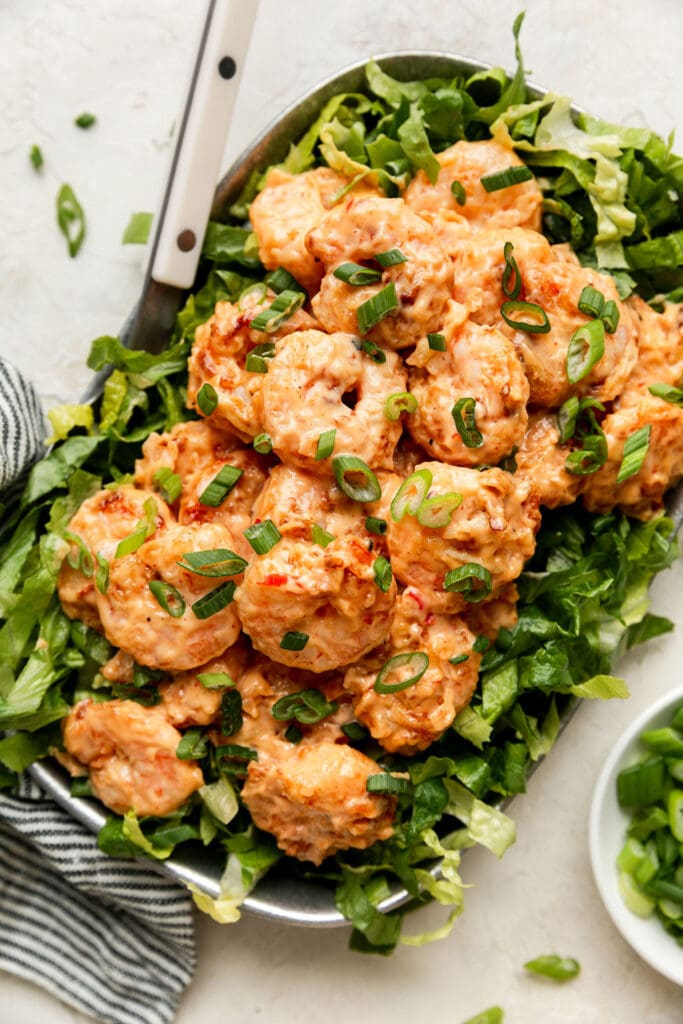 Overhead view of Bang Bang Shrimp on top of a bed of romaine lettuce topped with green onions. 
