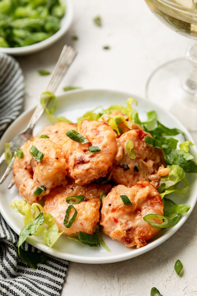Close up view of Bang Bang Shrimp on a bed of lettuces topped with green onions. 