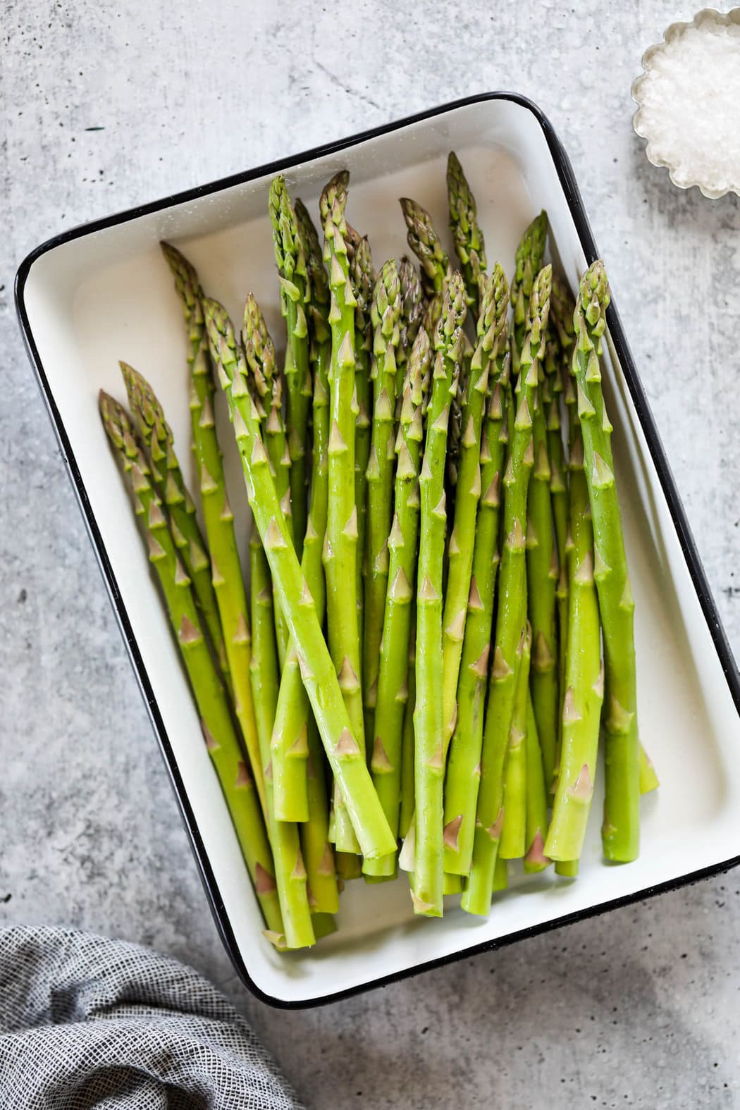 A white baking tray filled with fresh asparagus spears.