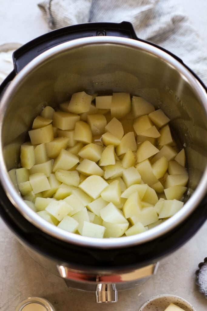 Overhead view of cut potatoes inside an Instant Pot ready to be cooked. 