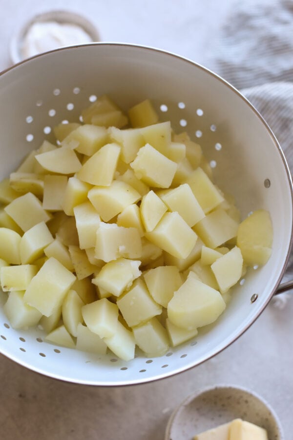 Cooked cubed potatoes in colander