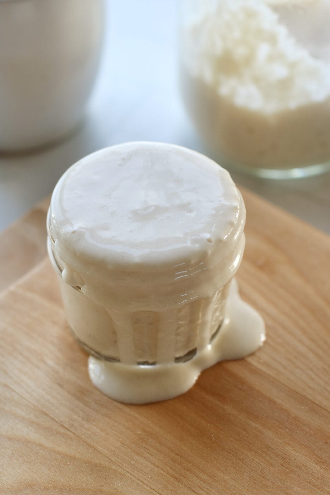 Close up view of sourdough starter bubbling over in a glass container.