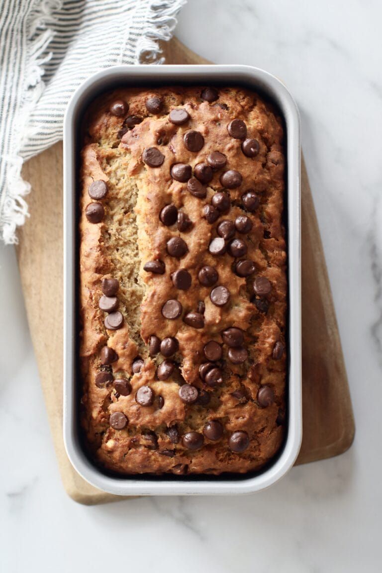 Overhead view of a freshly baked loaf of banana bread topped with chocolate chips.