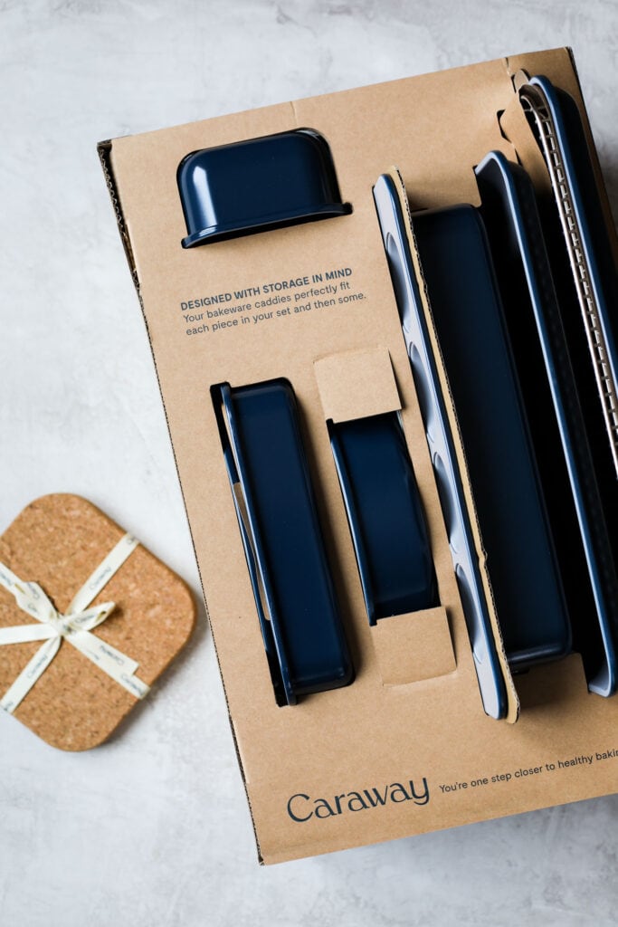 Overhead view of a navy blue caraway bakeware set being opened in the box. 