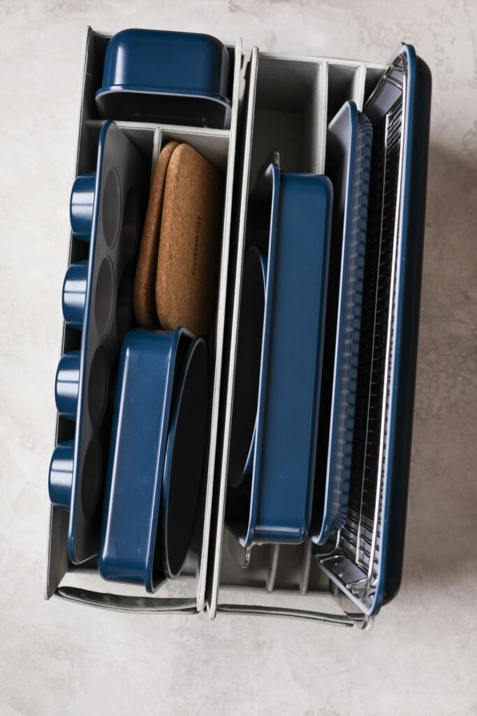 Overhead view of a navy-blue caraway bakeware set arranged in a storage organizer.
