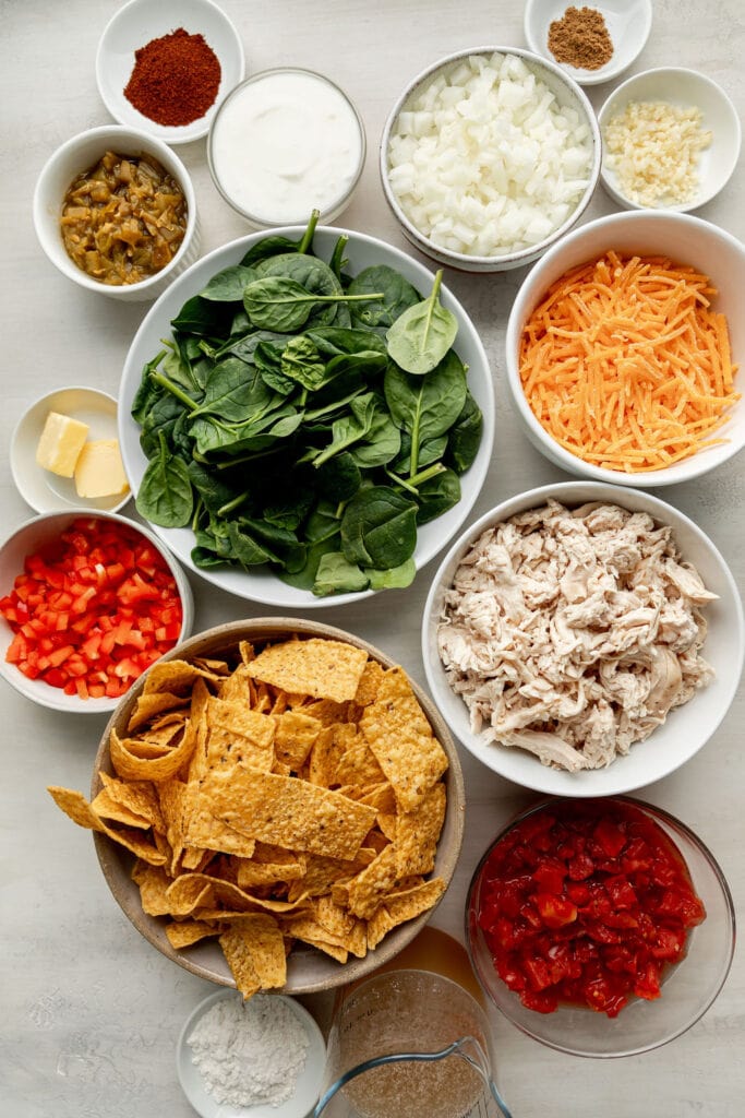 Overhead view of variety of ingredients for King Ranch Chicken in white bowls. 