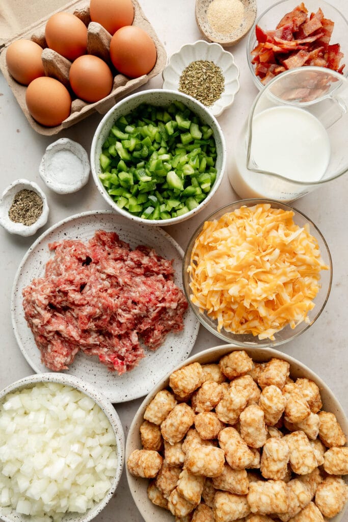 Overhead view of various ingredients for Tater Tot Breakfast Casserole in different bowls and containers. 