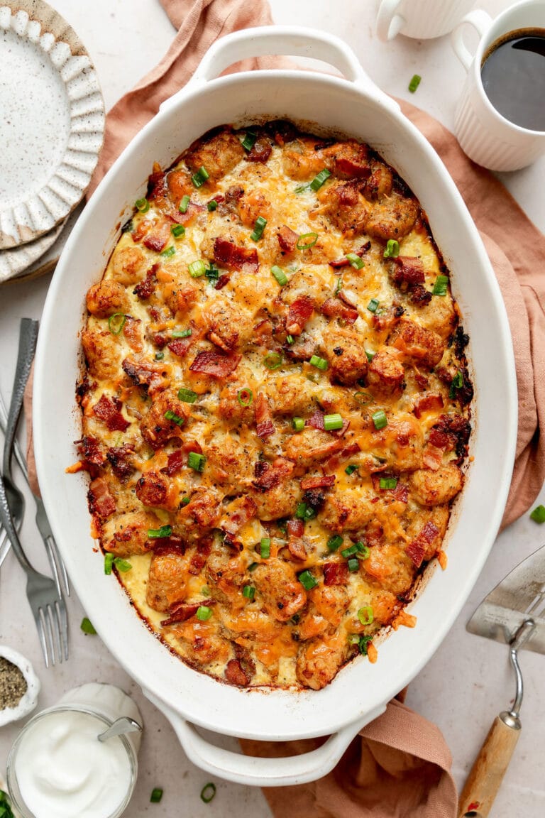 Overhead view of a freshly baked pan of tater tot breakfast casserole topped with fresh herbs and crispy bacon. 