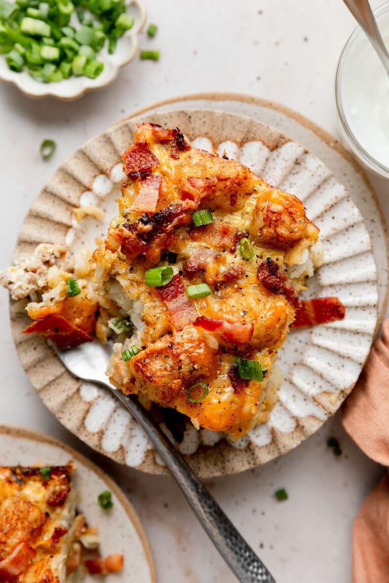 Overhead view of a plate of tater tot breakfast casserole topped with green onions and black pepper.