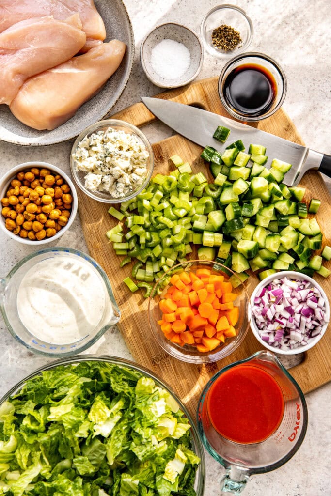 Overhead view of a variety of ingredients for buffalo chicken salad in glass bowls. 
