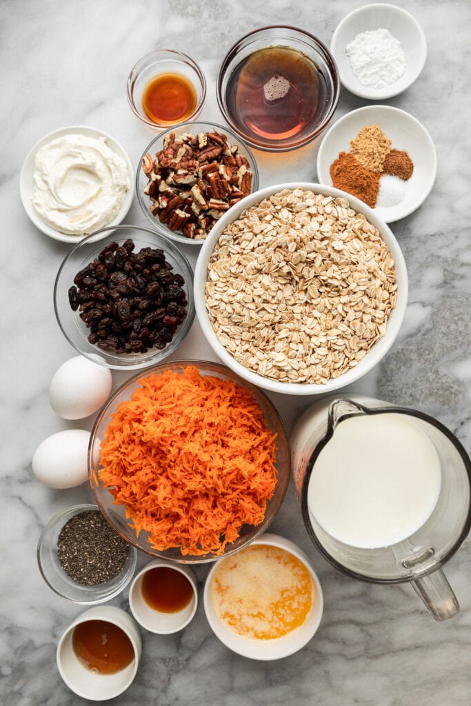 Overhead view of various ingredients for carrot cake baked oatmeal in different sized bowls. 