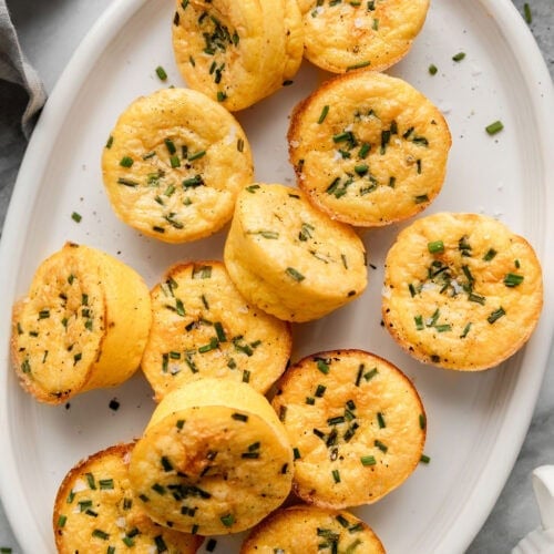 Cottage cheese egg bites topped with chives on white serving platter