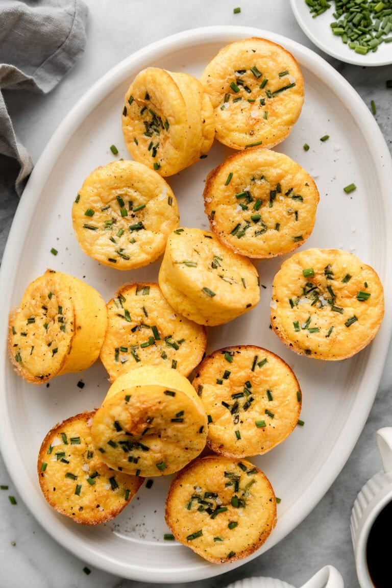 A large oval tray full of easy egg bites with cottage cheese topped with fresh chives. 