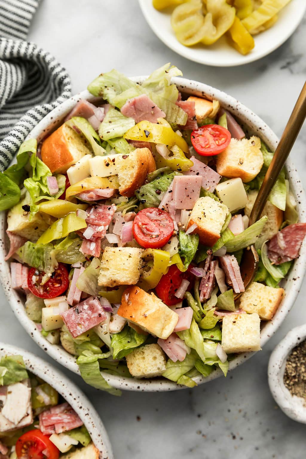 Close up view of a freshly tossed sub in a tub salad topped with fresh herbs and Italian dressing. 