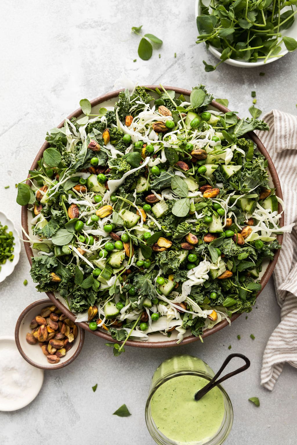 Overhead view of a large bowl of green goddess salad, all mixed up and ready for the dressing to be poured into.