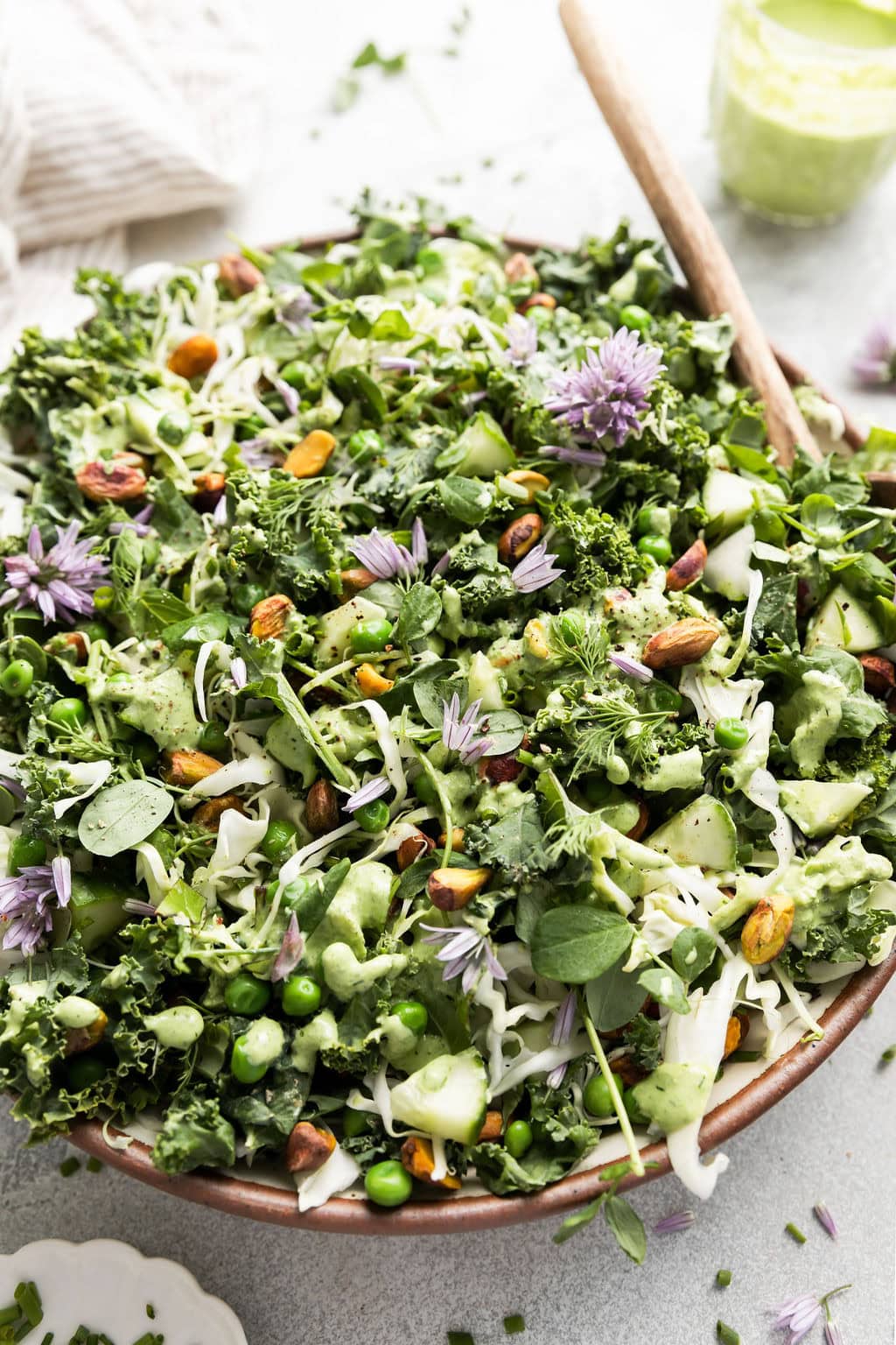 Close up view of a beautiful green goddess salad topped with purple chive flowers. 