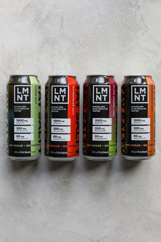 Four cans of LMNT sparkling water electrolyte cans on a marble background. 