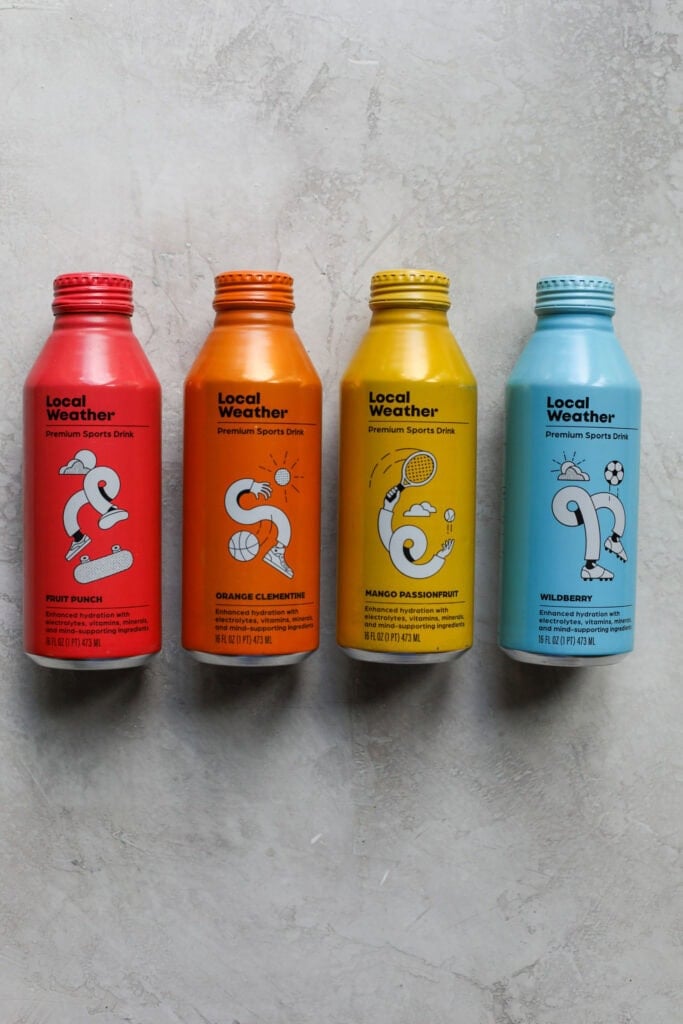 Four colorful bottles of Local Weather electrolyte drinks lined up on a marble background. 