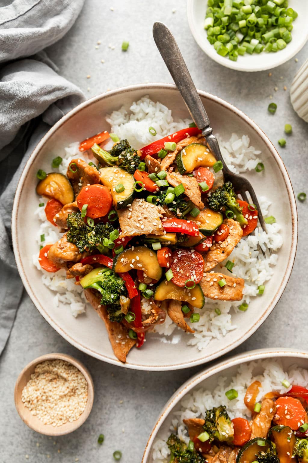 Serving of orange pork stir fry served over rice on a plate with a fork