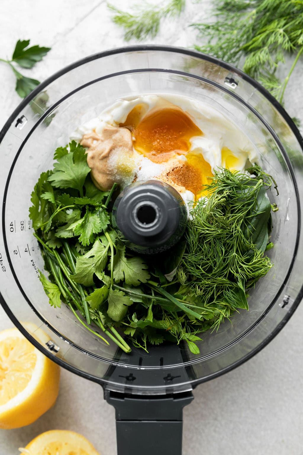 Overhead view of green goddess salad ingredients in a food processor ready to combine.