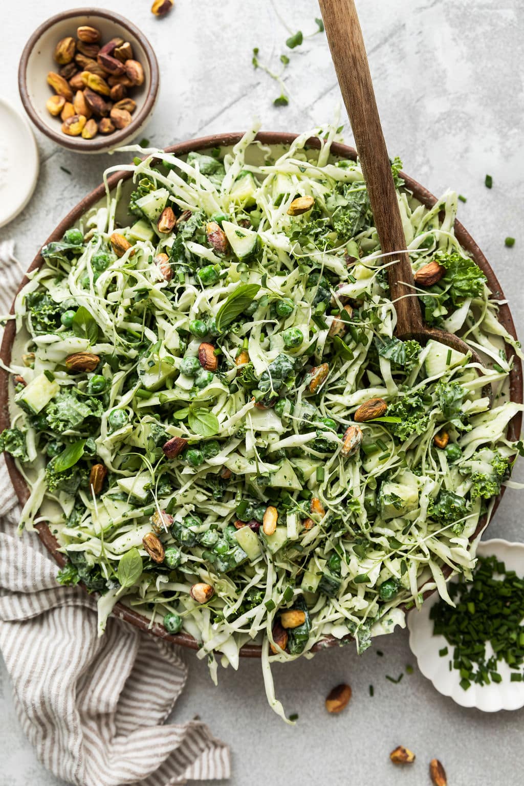 Overhead view of a large bowl of green goddess salad topped with pistachios. 