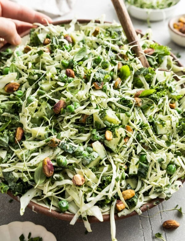 A bowl filled with Green Goddess salad topped with pistachios and micro greens