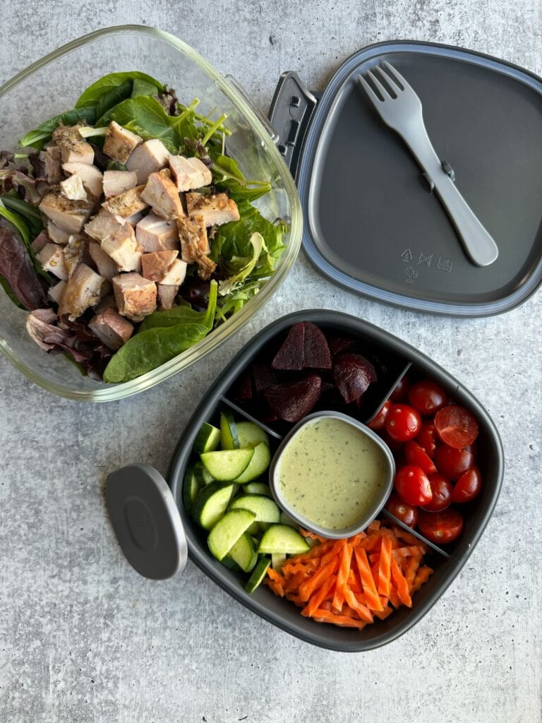 Overhead view of a meal prep container filled with separate salad ingredients in the different compartments. 