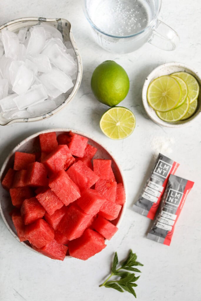 Overhead view all ingredients for watermelon mocktail arranged in bowls and pitchers