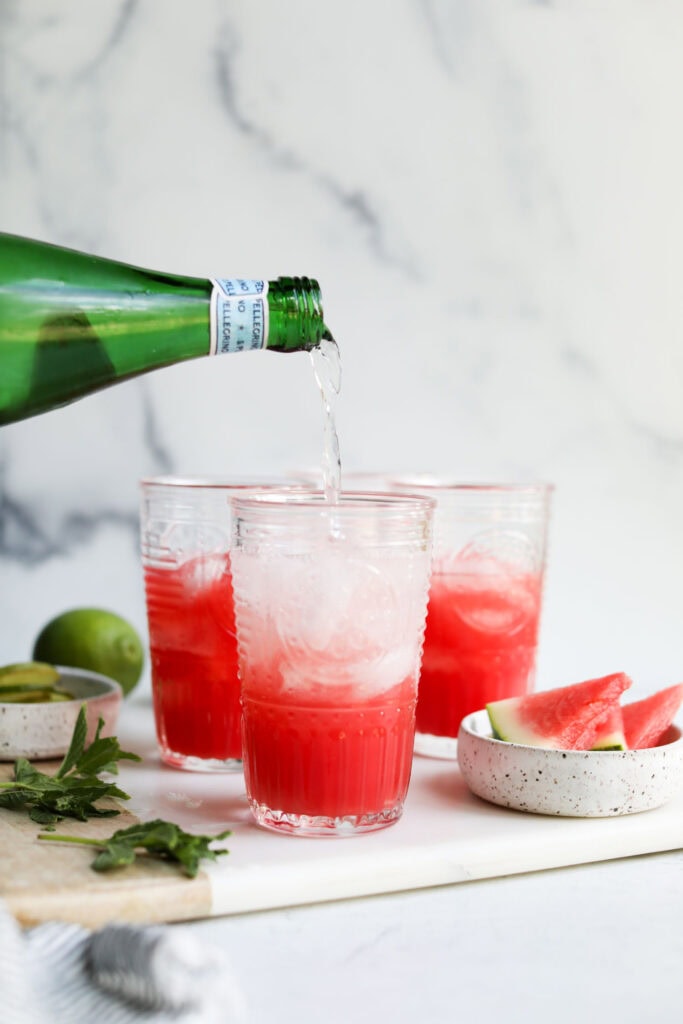 Sparkling water being poured into watermelon mocktail glasses