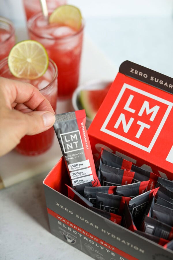 A watermelon LMNT electrolyte drink mix packet being removed from a box of packets