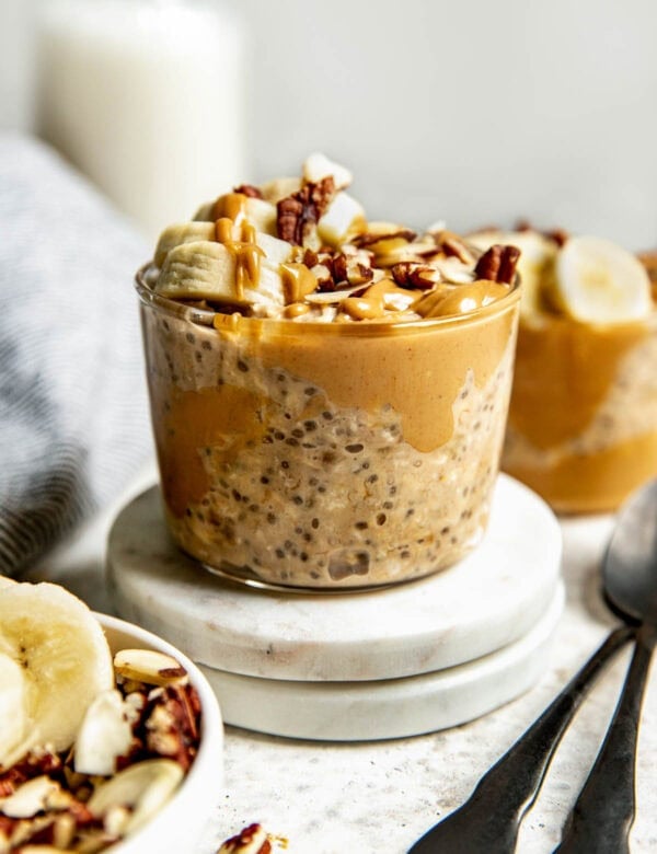 short glass jar filled with peanut butter overnight oats topped with banana slices and chopped walnuts.