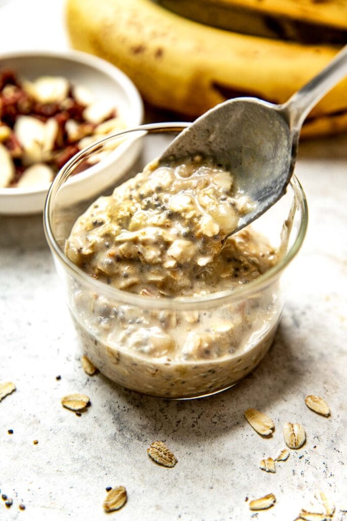 Spoonful of peanut butter banana overnight oats being spooned into a small glass jar