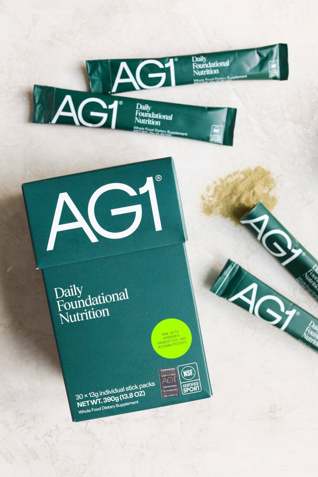 Four packets of AG1 Next Gen, one spilled on a counter and a box of AG1.