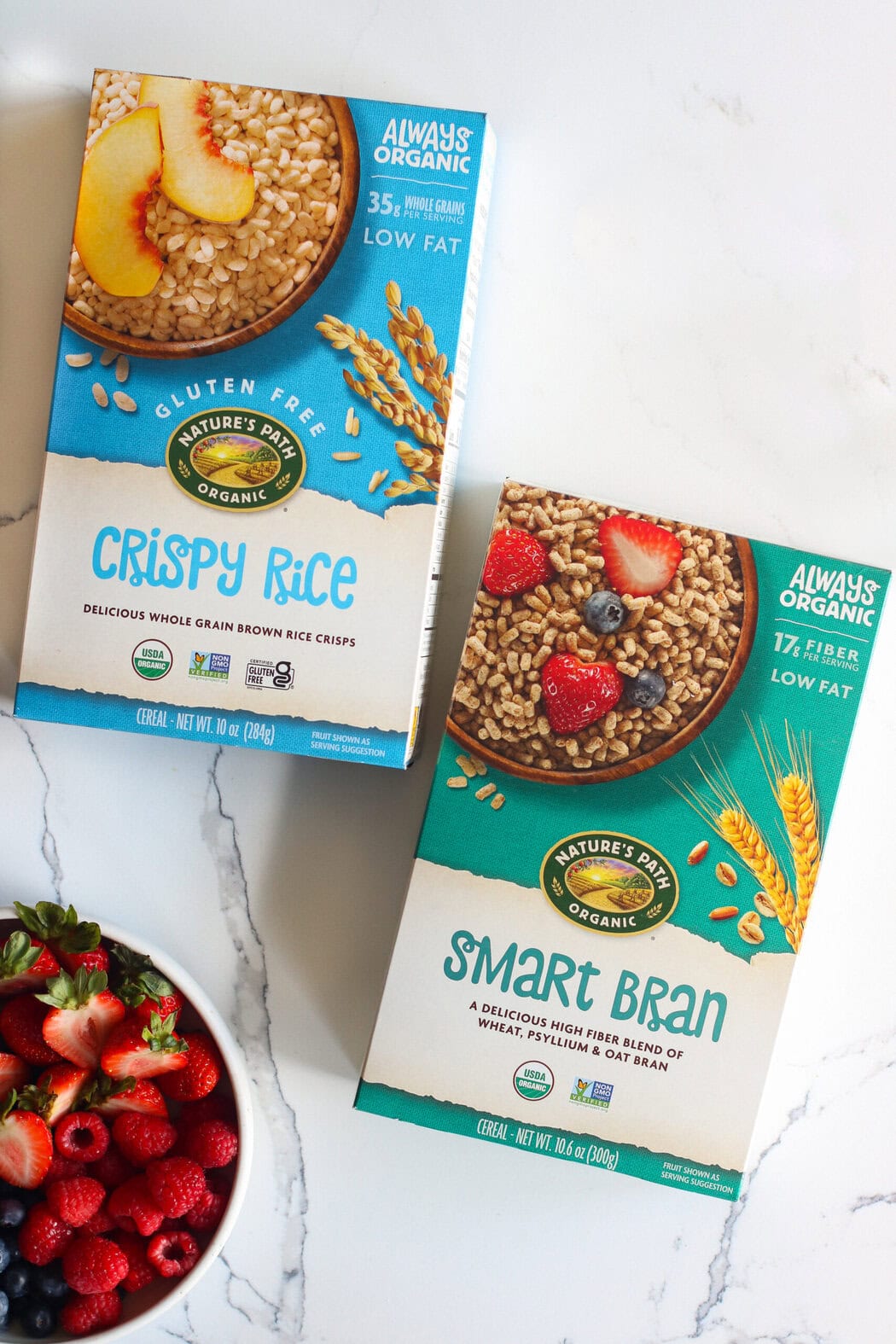 Overhead view of 2 boxes of nature's path organic cereals next to a bowl of fresh berries. 