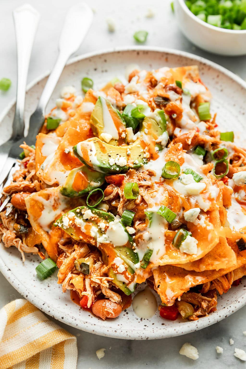 Close up view of a plate of Easy Buffalo Chicken Enchiladas topped with sliced avocado. 