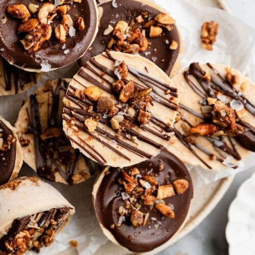 Several frozen protein peanut butter cups topped with chocolate and granola on a plate for serving.