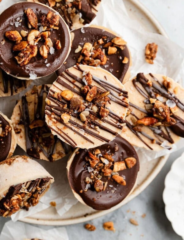 Several frozen protein peanut butter cups topped with chocolate and granola on a plate for serving.