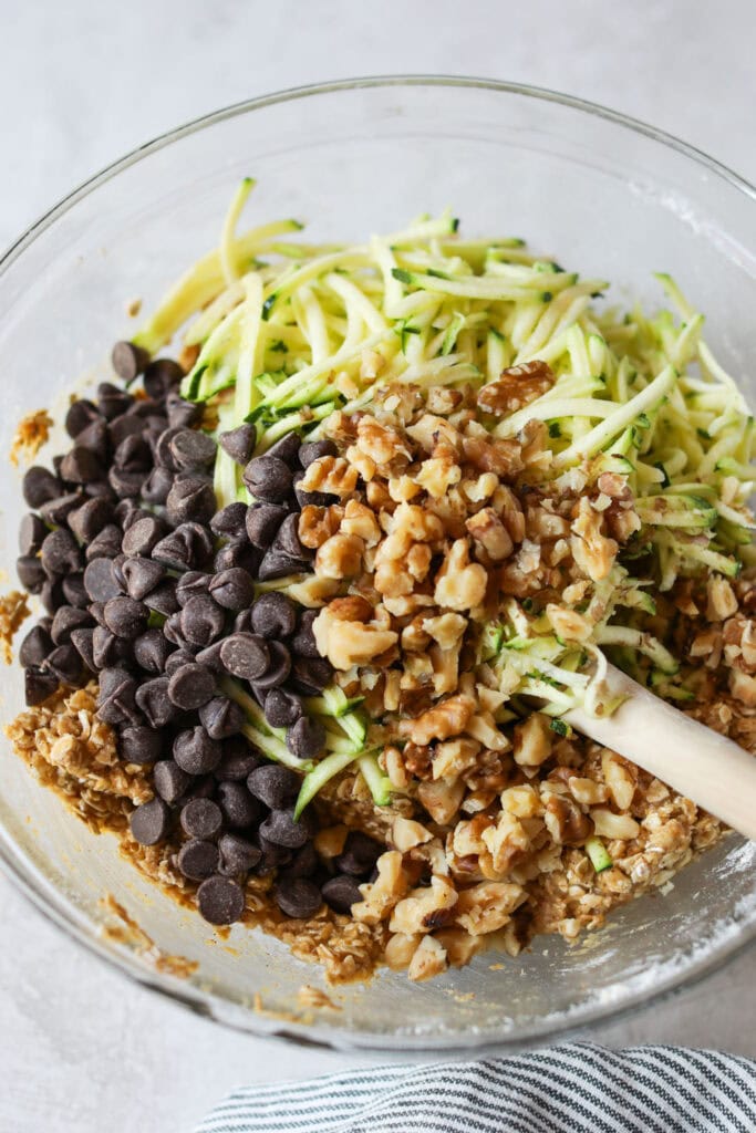 A glass bowl filled with ingredients for Zucchini Breakfast Cookies, ready for mixing. 