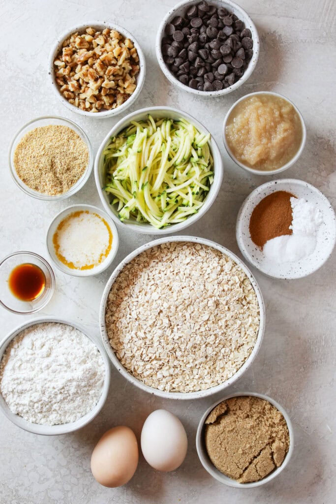 Overhead view of a variety of ingredients in separate bowls for Zucchini Breakfast Cookies. 