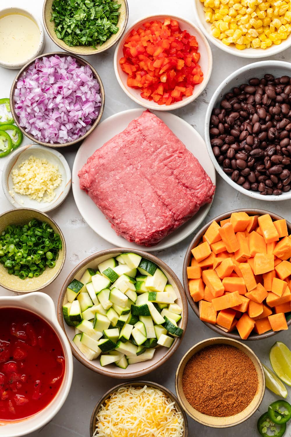 Overhead view of a variety of ingredients for Ground Beef and Zucchini Skillet in different sized bowls. 