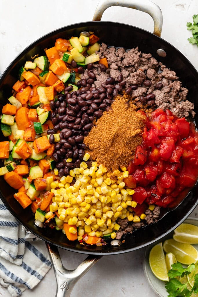 Overhead view of a pan with Ground Beef and Zucchini Skillet ingredients ready to be stirred. 