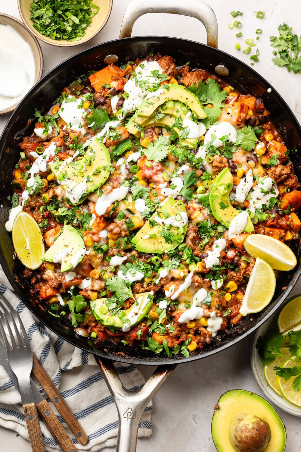 Overhead view of a cast iron pan filled with Ground Beef and Zucchini Skillet (Mexican-Inspired Flavors). Topped with sliced avocado and fresh cilantro. 