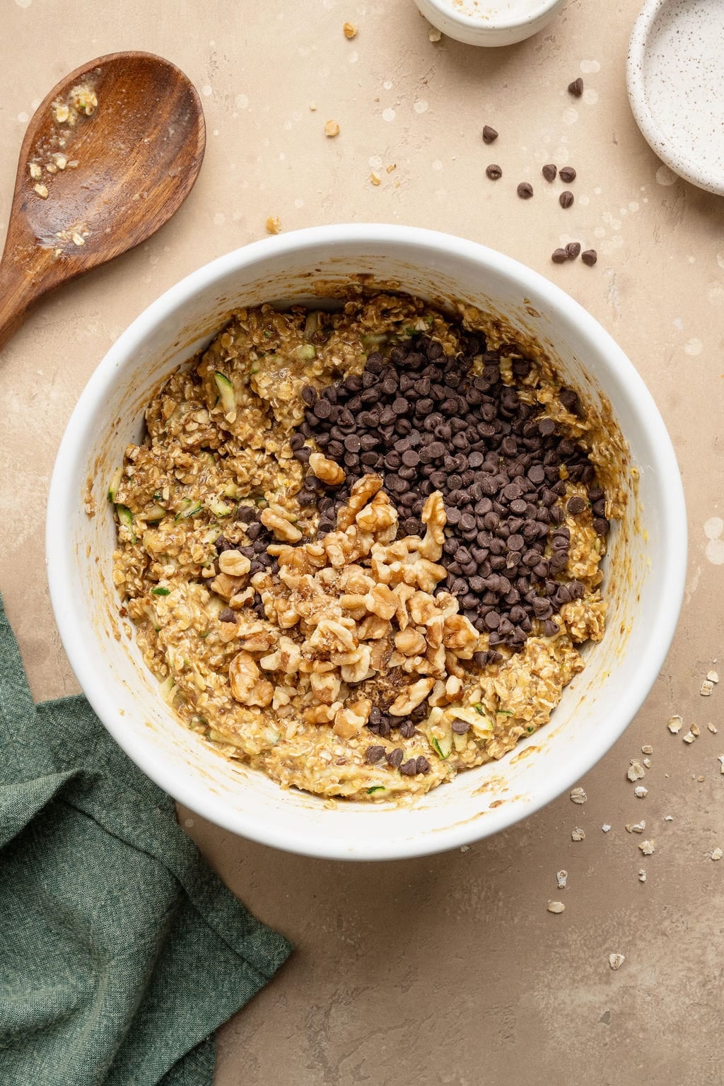 Walnuts and chocolate chips on top of batter to make zucchini breakfast cookies in a bowl.