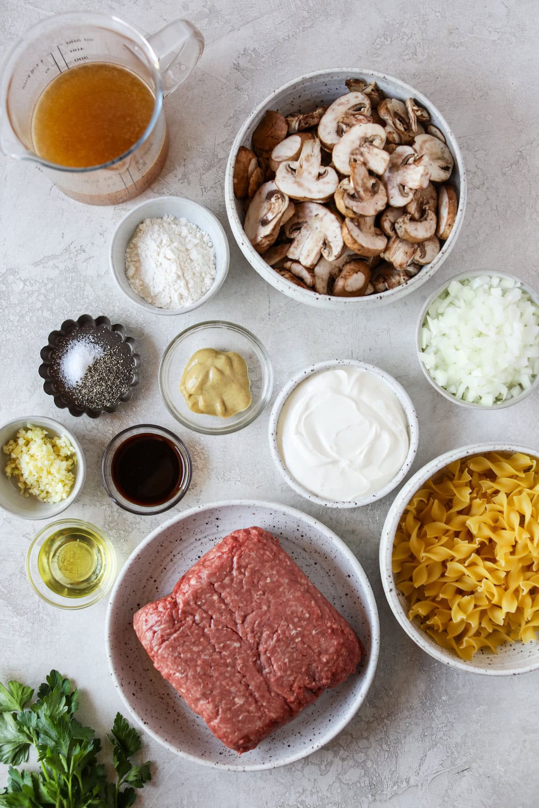 Overhead view of a variety of ingredients for ground beef stroganoff in different sized bowls. 