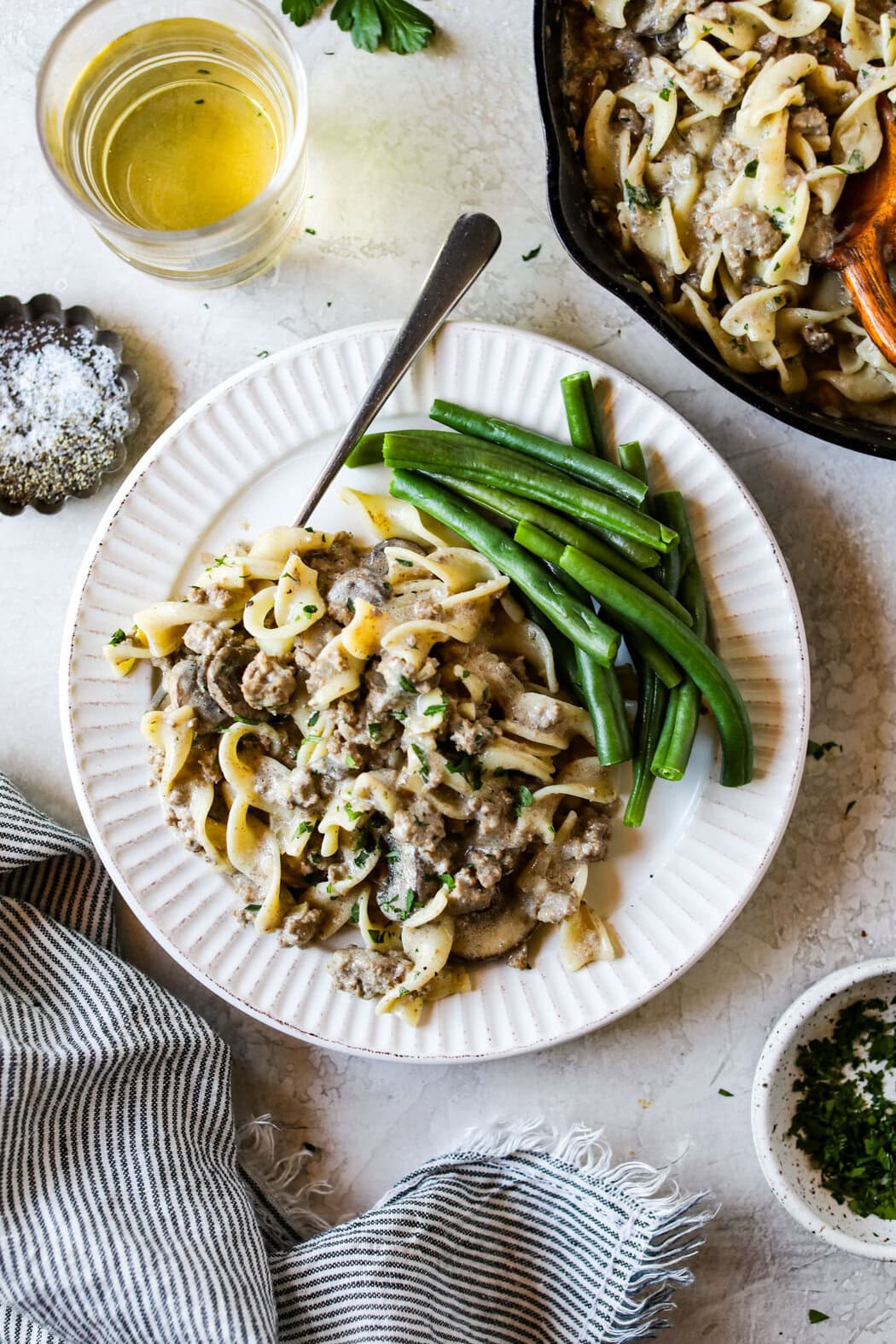 Overhead view of Easy and Delicious Ground Beef Stroganoff on a white plate with green beans on the side. 